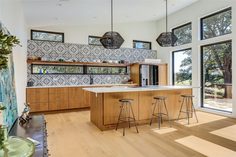 Kitchen featuring light wood-style floors, brown cabinetry, a kitchen bar, refrigerator with ice dispenser, and a center island