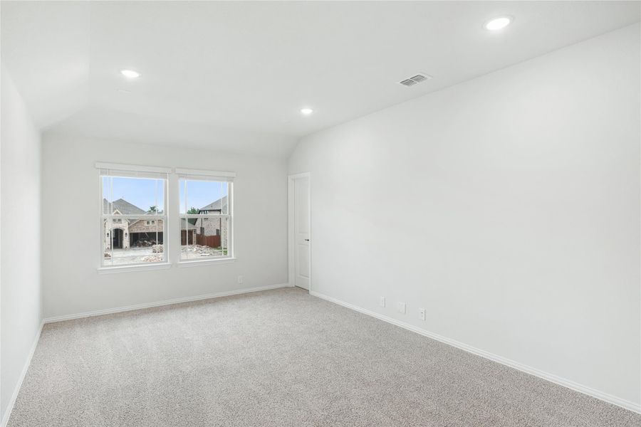 Empty bedroom with vaulted ceiling, carpet flooring, recessed lighting, and two windows Empty bedroom with vaulted ceiling, carpet flooring, recessed lighting, and two windows