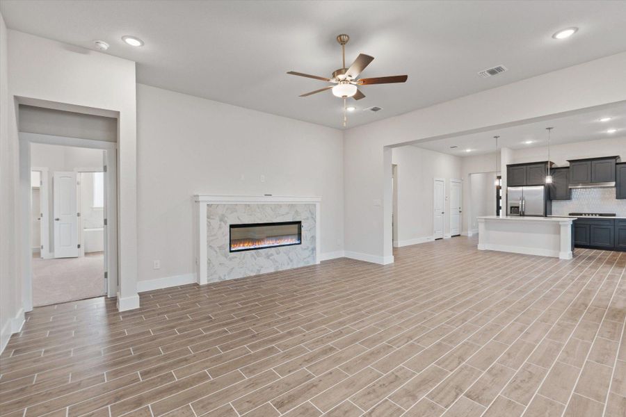 An open floorplan seamlessly connects the living area with a sleek fireplace and a modern kitchen.