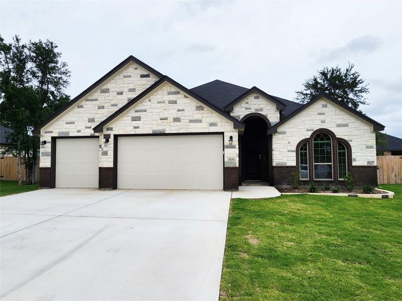 A well-maintained facade showcasing a blend of stone and brick, with a concrete driveway leading to two garage doors. A well-maintained facade showcasing a blend of stone and brick, with a concrete driveway leading to two garage doors.