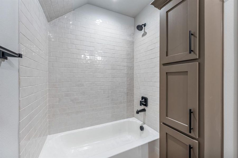 Bathroom with tiled shower / bath and lofted ceiling