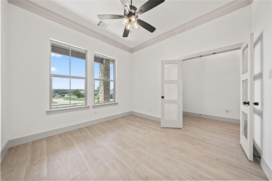 Unfurnished bedroom featuring light wood-type flooring, ceiling fan, and crown molding Unfurnished bedroom featuring light wood-type flooring, ceiling fan, and crown molding