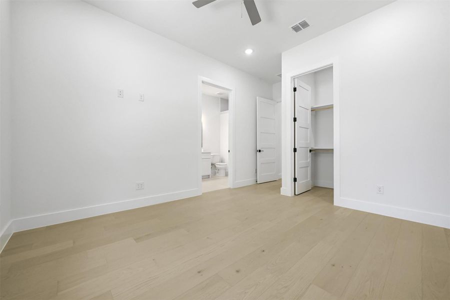 Unfurnished bedroom with light wood finished floors, connected bathroom, a walk in closet, recessed lighting, and a ceiling fan