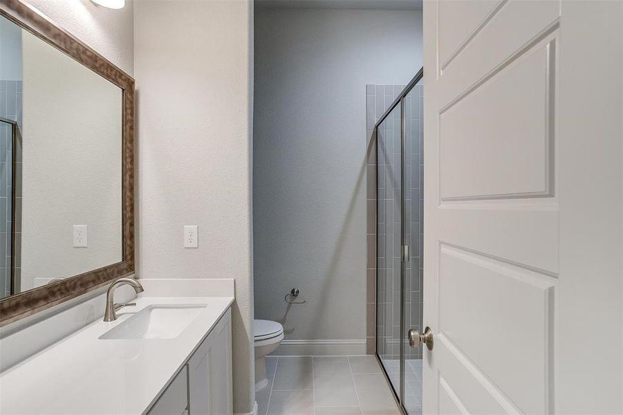 Bathroom featuring tile patterned floors, vanity, walk in shower, and toilet