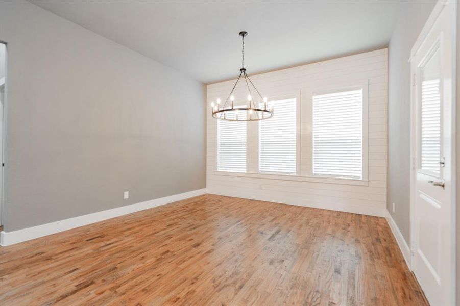 Spare room with baseboards, a chandelier, and light wood-style floors Spare room with baseboards, a chandelier, and light wood-style floors