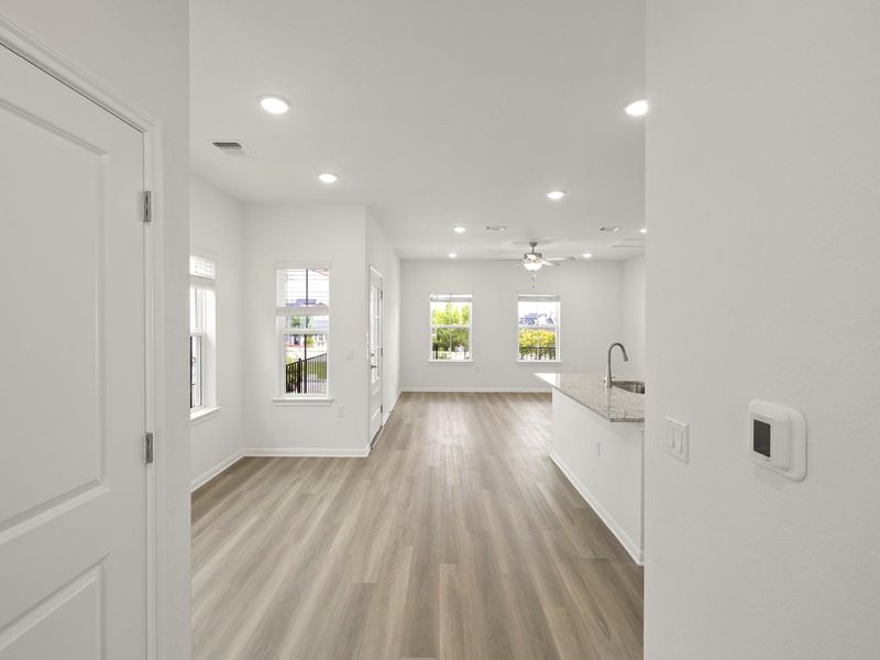 An open floorplan living area features light-toned flooring and an integrated kitchen island with granite counters.