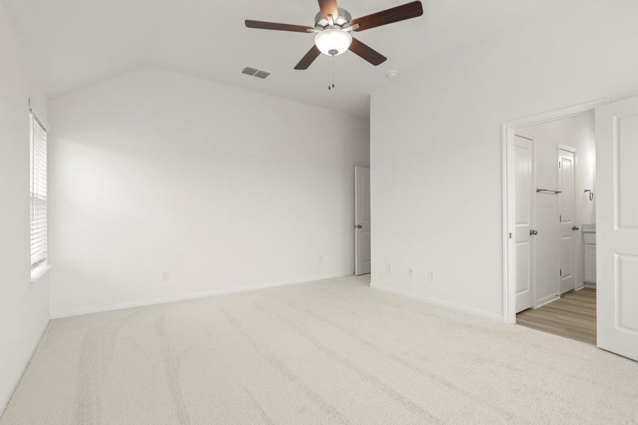 Unfurnished bedroom with light colored carpet, ceiling fan, vaulted ceiling, and connected bathroom