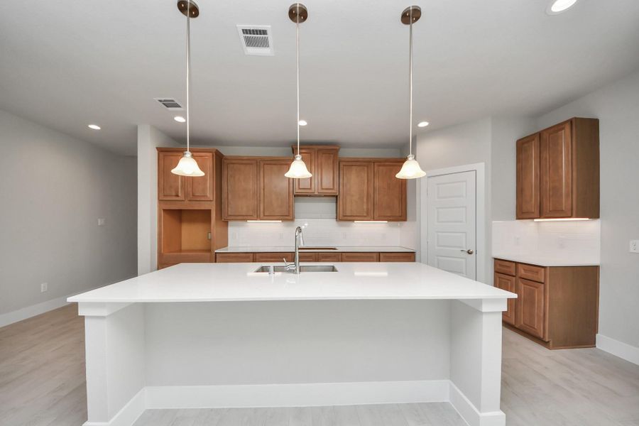 The kitchen is a culinary haven, featuring granite countertops, a tile backsplash, stainless steel appliances, 42” upper cabinets, and undercabinet lighting. Sample photo of completed home with similar floor plan. Actual colors and selections may vary. The kitchen is a culinary haven, featuring granite countertops, a tile backsplash, stainless steel appliances, 42” upper cabinets, and undercabinet lighting. Sample photo of completed home with similar floor plan. Actual colors and selections may vary.