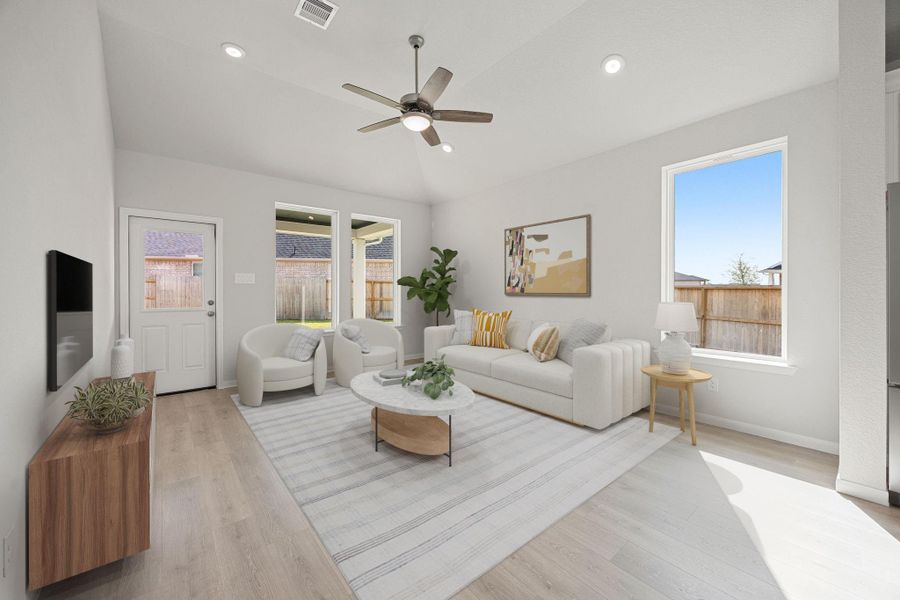 A bright and inviting open-concept living area features durable, wood-look flooring, a neutral gray color palette, and high ceilings that enhance the sense of space. Abundant natural light streams in through multiple large windows and a glass-paneled back door, complemented by overhead recessed lighting and a modern ceiling fan, creating a comfortable and versatile space for everyday living and entertaining. A bright and inviting open-concept living area features durable, wood-look flooring, a neutral gray color palette, and high ceilings that enhance the sense of space. Abundant natural light streams in through multiple large windows and a glass-paneled back door, complemented by overhead recessed lighting and a modern ceiling fan, creating a comfortable and versatile space for everyday living and entertaining.