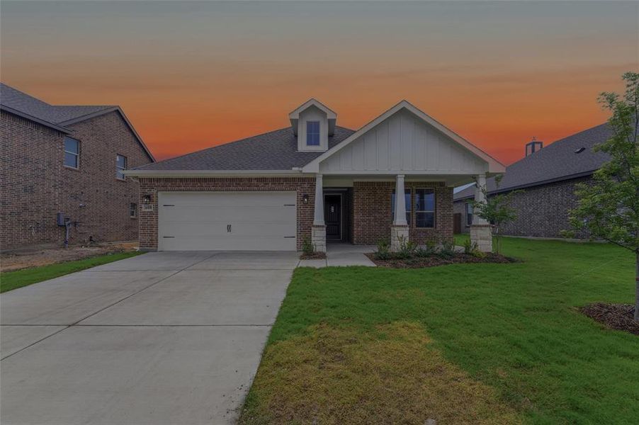 Brick and siding exterior featuring a two-car garage, covered porch, and concrete driveway