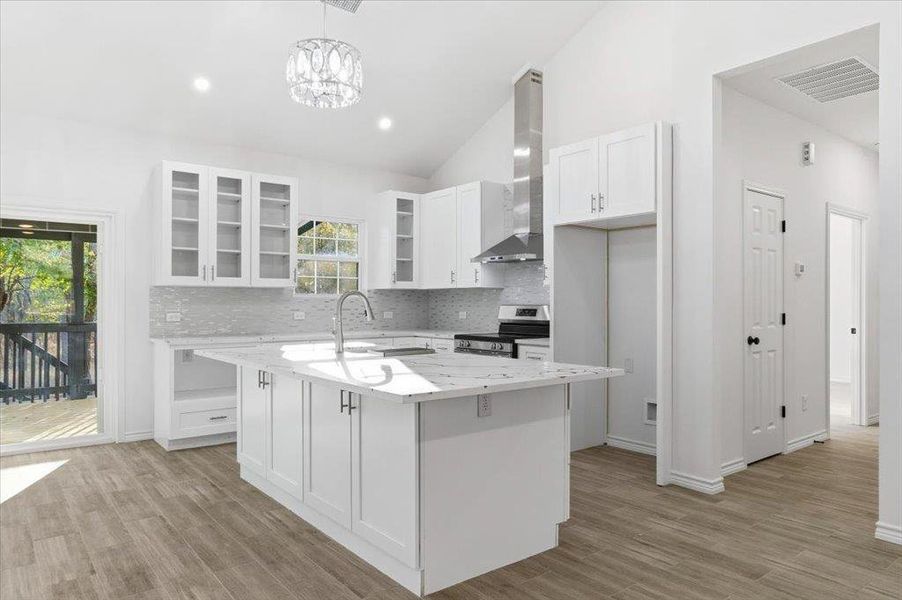 Kitchen with glass insert cabinets, vaulted ceiling, pendant lighting, tasteful backsplash, and stainless steel range with electric stovetop