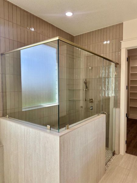 Bathroom featuring a textured ceiling, a stall shower, and a walk in closet