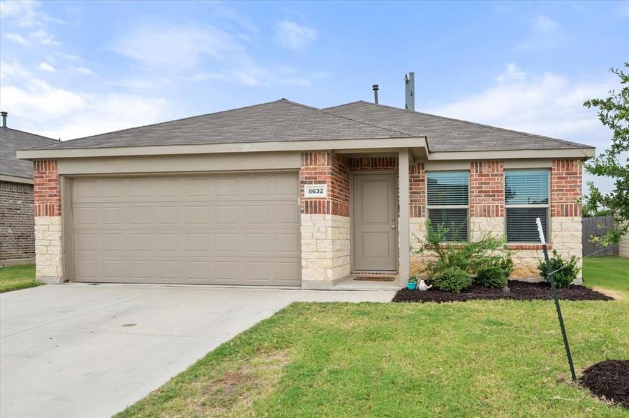 View of front of home with brick siding, an attached garage, a shingled roof, and driveway