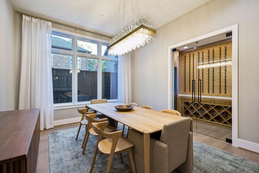 The dining room showcases a striking wine cellar and is filled with abundant natural light.