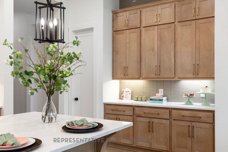 Kitchen featuring decorative light fixtures, backsplash, a chandelier, and light brown cabinets