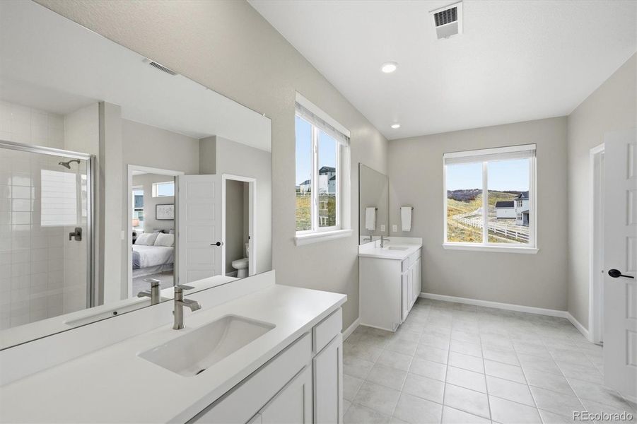 Primary bathroom with separate vanities, quartz counter tops, private water closet, shower and large walk in closet