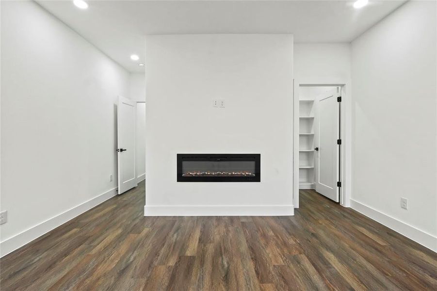 Unfurnished living room with a glass covered fireplace, recessed lighting, and dark wood-style floors Unfurnished living room with a glass covered fireplace, recessed lighting, and dark wood-style floors