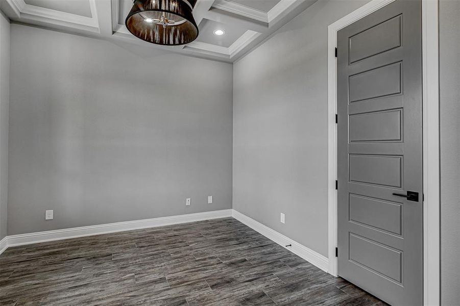 Spare room with dark wood-type flooring, an inviting chandelier, ornamental molding, beam ceiling, and coffered ceiling