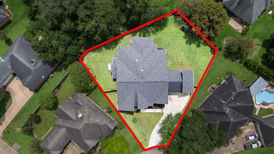 This aerial view shows a house with a distinctive roof shape, situated on a spacious, fenced lot. The property features a large backyard with mature trees and ample green space, ideal for outdoor activities. The surrounding neighborhood is well-maintained. This aerial view shows a house with a distinctive roof shape, situated on a spacious, fenced lot. The property features a large backyard with mature trees and ample green space, ideal for outdoor activities. The surrounding neighborhood is well-maintained.