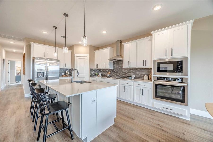 Kitchen featuring decorative backsplash, wall chimney exhaust hood, light hardwood / wood-style floors, sink, and stainless steel appliances