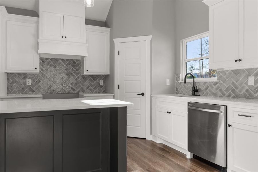 Kitchen with white cabinets, light stone counters, and dishwasher