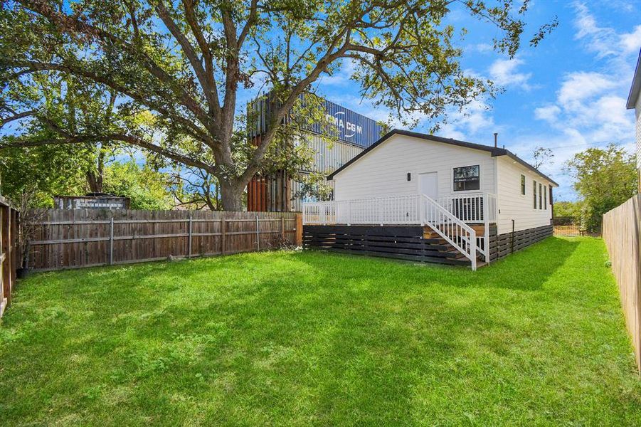 Modern single-family home with a fresh exterior, featuring a covered front porch and a secure black fence. The property is situated on a corner lot with a clear sky above.