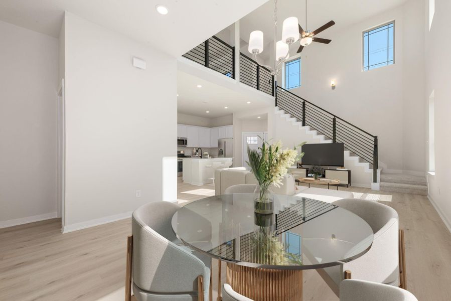 This elegant dining area flows effortlessly into the open living space, enhanced by soaring ceilings and modern railing details. Bright natural light and sleek finishes make this the perfect spot to enjoy meals or entertain in style.