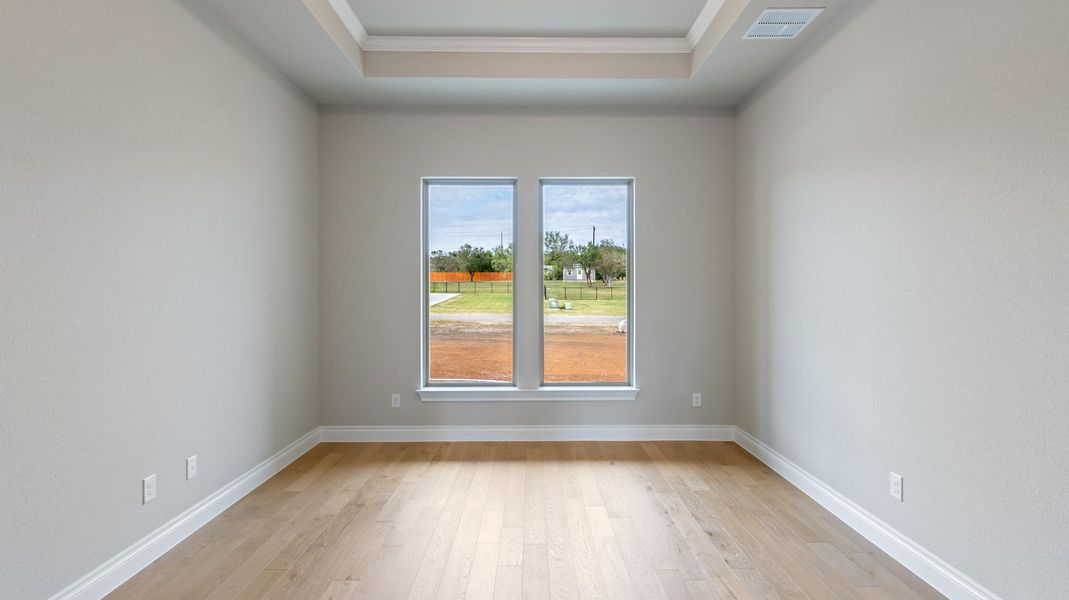 Unfurnished room with light wood-type flooring, crown molding, and a raised ceiling