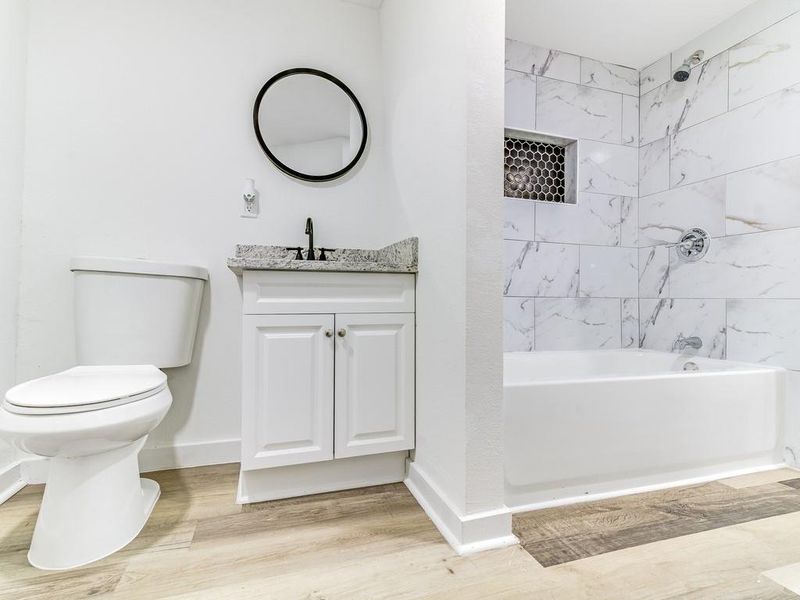 Full bathroom with vanity, shower combination, and wood finished floors Full bathroom with vanity, shower combination, and wood finished floors