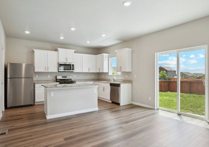 The kitchen has stainless steel appliances and plank flooring.