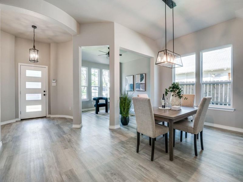 Dining area featuring arched walkways, ceiling fan with notable chandelier, light wood finished floors, and baseboards Dining area featuring arched walkways, ceiling fan with notable chandelier, light wood finished floors, and baseboards