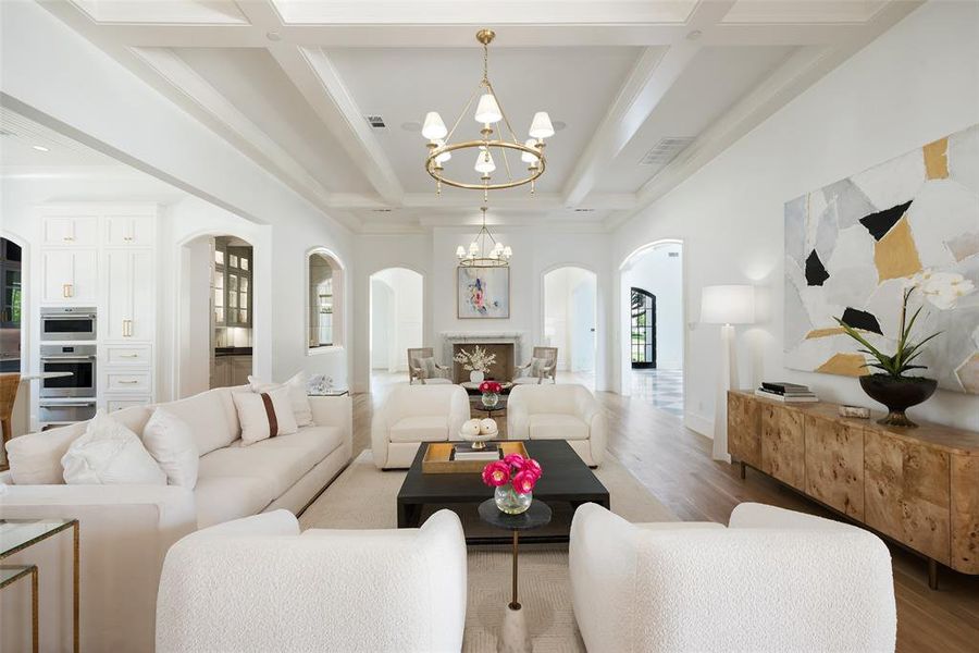 Living room with a chandelier, beamed ceiling, light hardwood / wood floors, and coffered ceiling