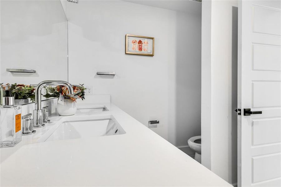 Bathroom featuring dual sinks, oversized vanity, and toilet