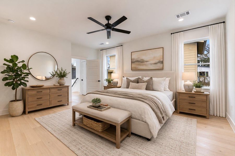 Staged photo. The primary suite is located upstairs and has large windows that frame the surrounding neighborhood, while the expansive floor plan offers plenty of room for a king-sized retreat and a sitting area.