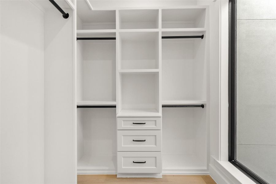 Keeping everything organized is effortless with your custom walk-in closet, complete with built-in shelving, drawers, and generous hanging space, all illuminated by a large window that fills the space with natural light.