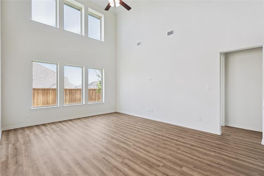 Unfurnished room with wood-type flooring, ceiling fan, and a high ceiling