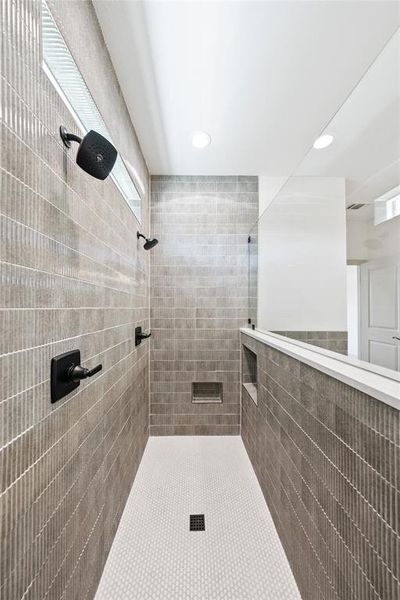 Bathroom featuring tiled shower, recessed lighting, tile walls, and tile patterned floors