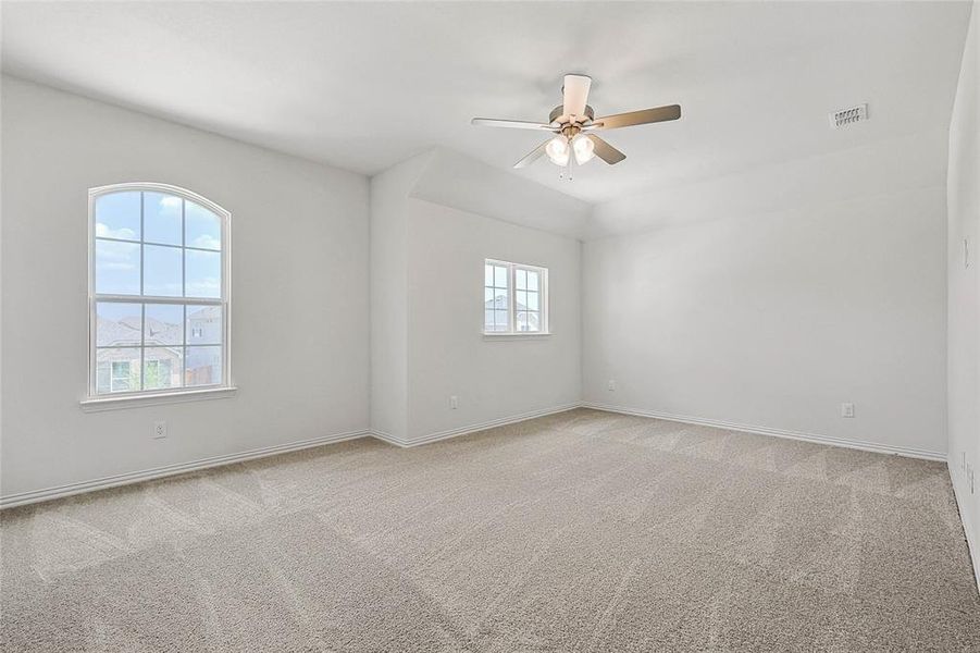 Spare room featuring light colored carpet, plenty of natural light, and ceiling fan