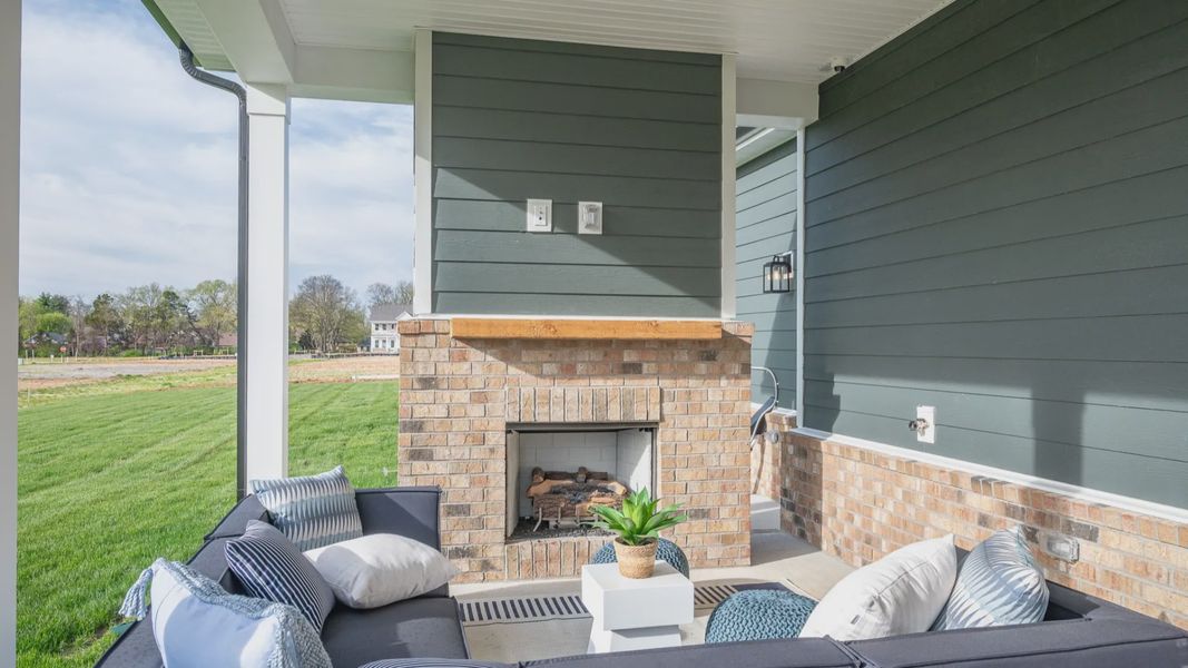 Covered outdoor seating area with fireplace and mantel and outdoor sectional