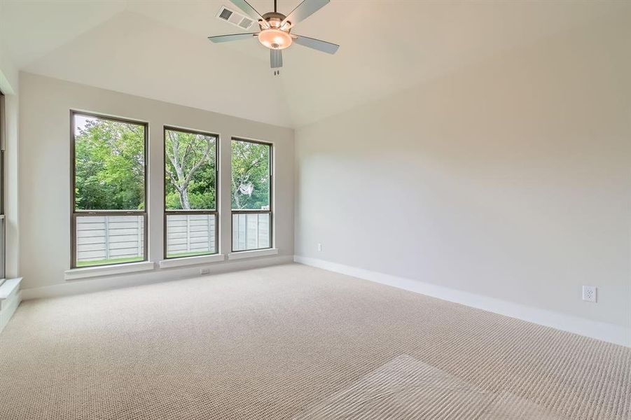 Carpeted empty room with a ceiling fan and high vaulted ceiling Carpeted empty room with a ceiling fan and high vaulted ceiling