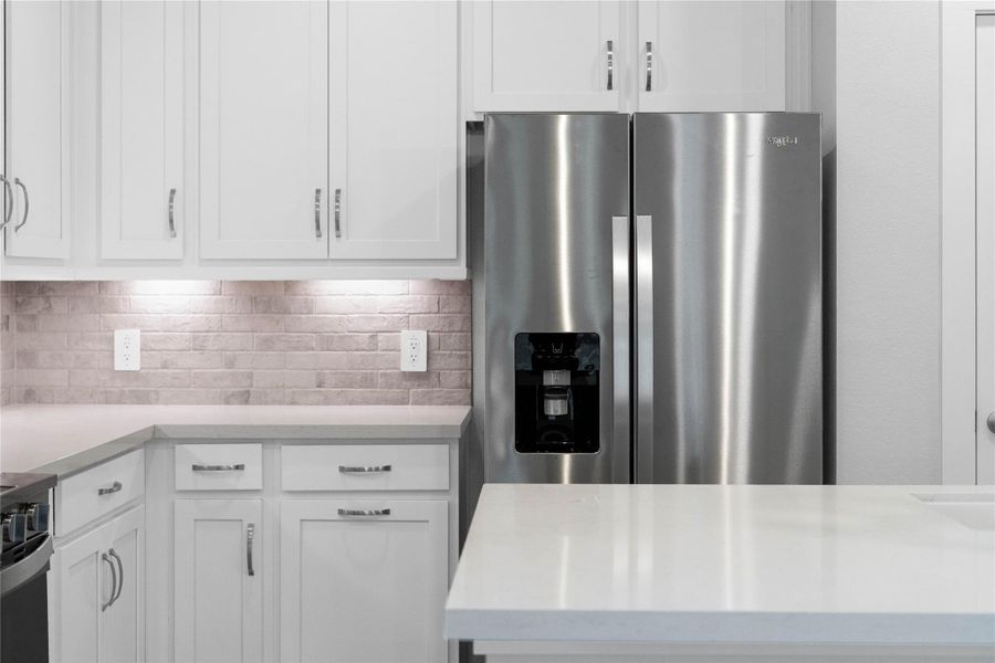 Kitchen comes equipped with a side-by-side Whirlpool refrigerator.