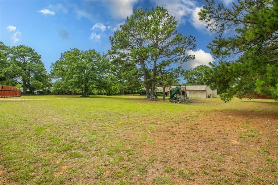 Expansive yard offers open space, mature trees, and easy access to the workshop building. Expansive yard offers open space, mature trees, and easy access to the workshop building.