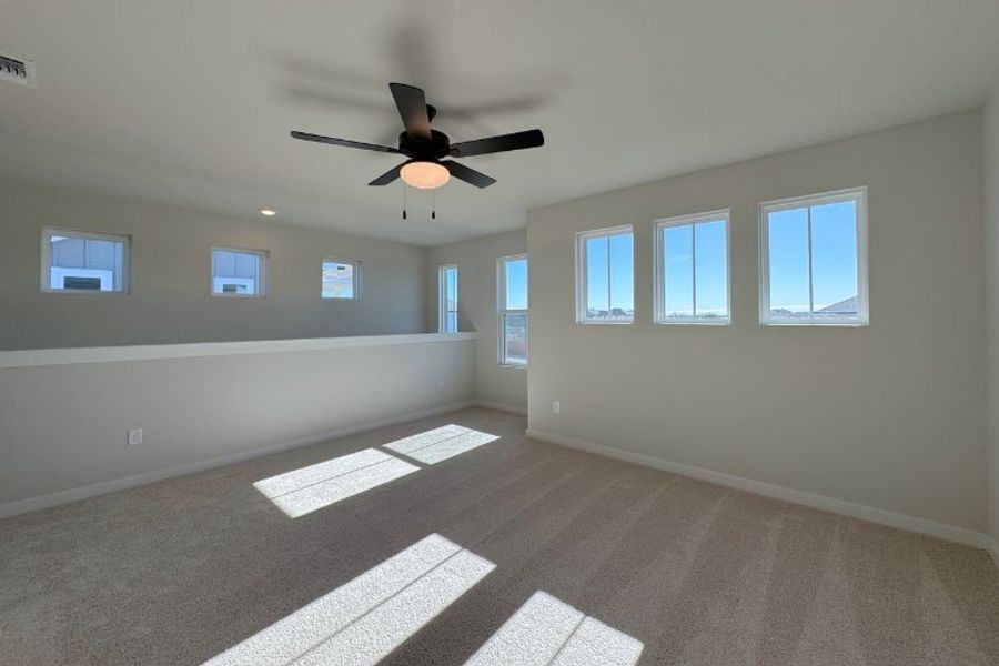 A room with a ceiling fan and windows.