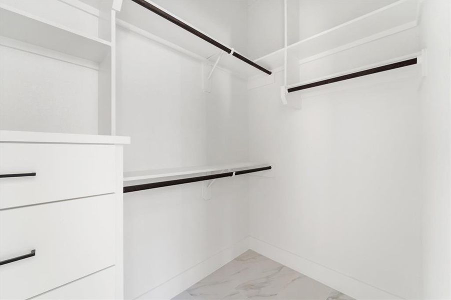 The primary bedroom's walk in closet features built in drawers and shelving.