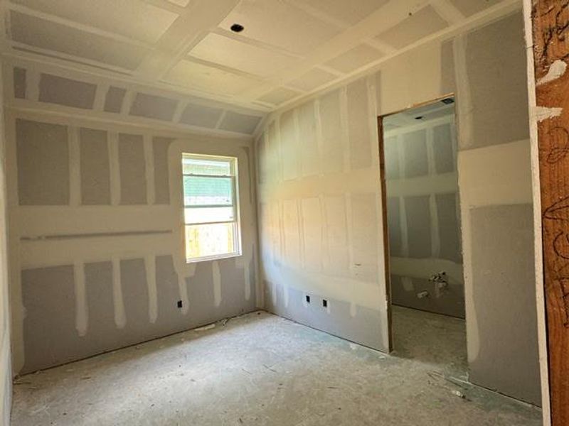 A well-proportioned bedroom awaiting personalized finishes, offering a glimpse into its connected bathroom.