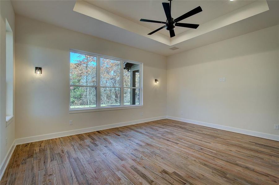 Primary bedroom has windows on two walls, trey ceiling, red oak floors, and enough space for king size bed plus a seating area.