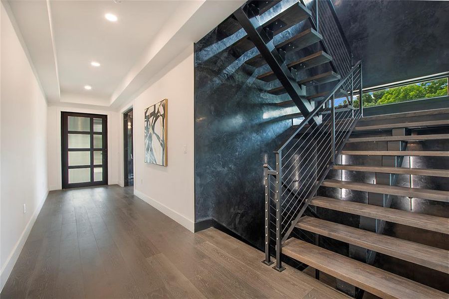 Staircase with a tray ceiling and hardwood / wood-style flooring