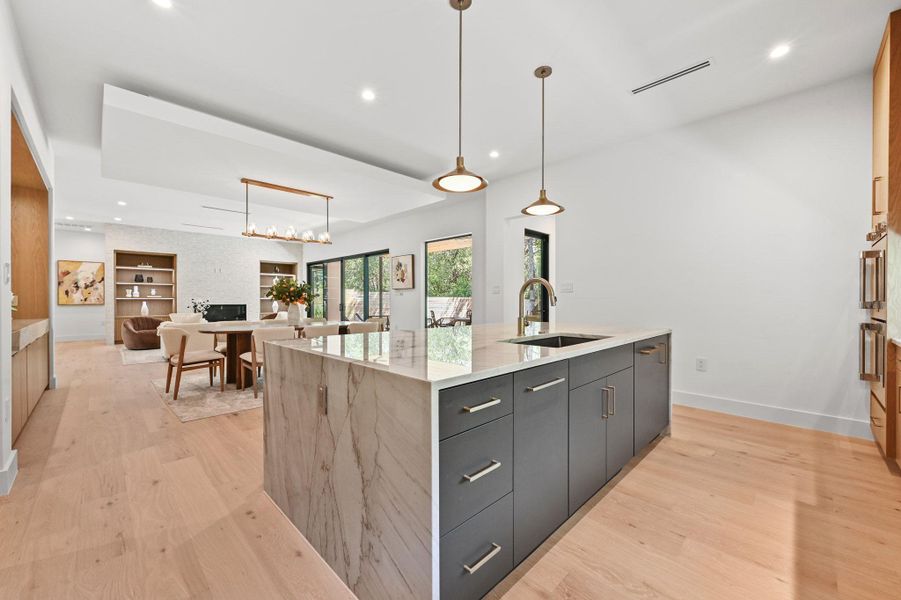 Kitchen with recessed lighting, light wood-style flooring, decorative light fixtures, an island with sink, and open floor plan