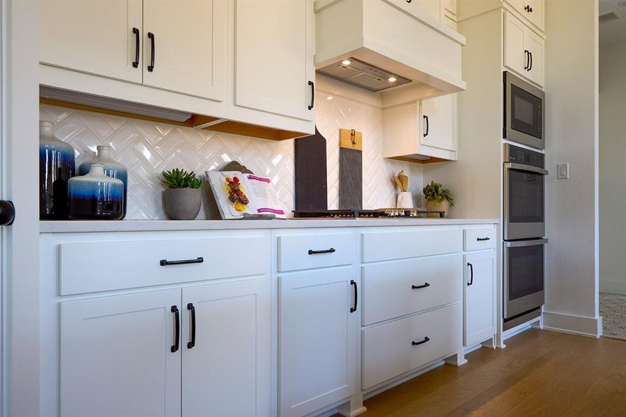 Kitchen with white cabinets and custom range hood