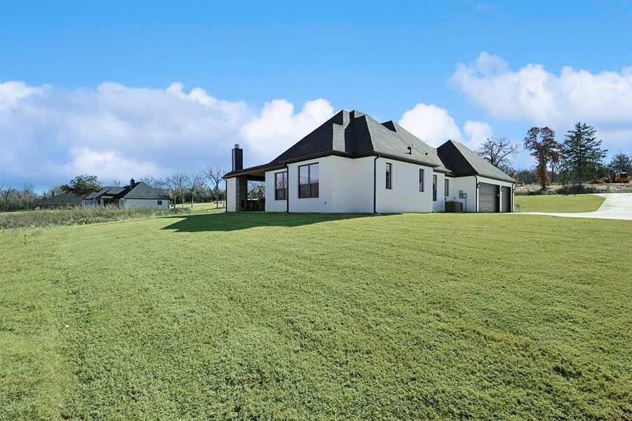 View of home's exterior featuring a yard, a garage, roof with shingles, a chimney, and driveway View of home's exterior featuring a yard, a garage, roof with shingles, a chimney, and driveway